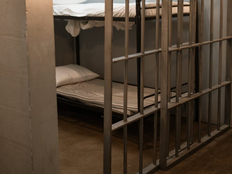 a bunk bed with striped linen behind bars