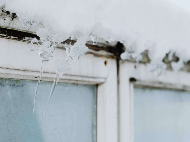 close up of little icicles and snow above a window