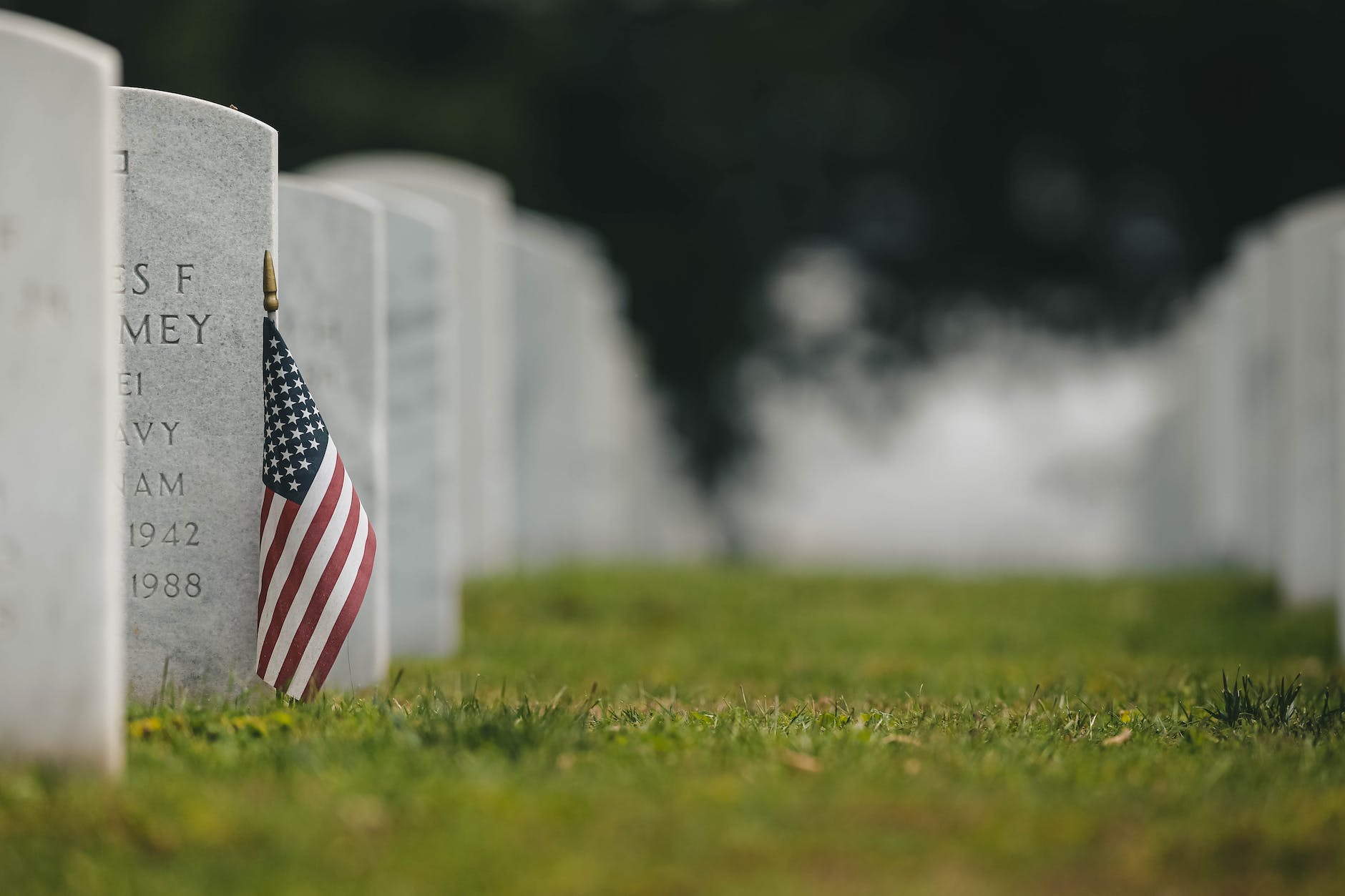 american flag near the tombstone on the green grass